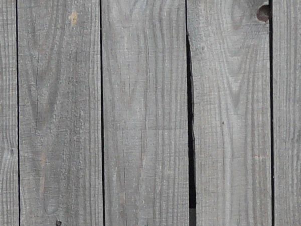 Thin grey planks installed evenly and vertically with dark streaks coming from nails.